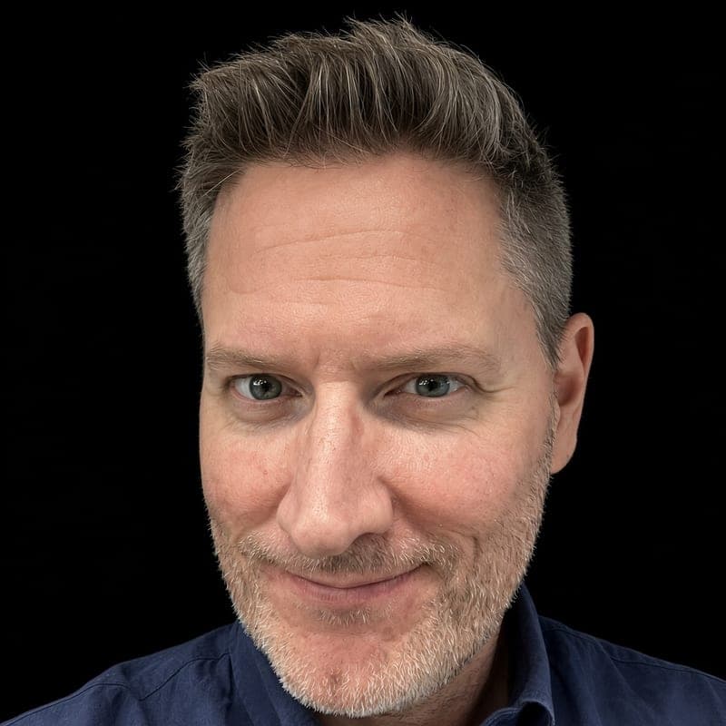 Michael Order, founder of Vibing Legends, smiling at the camera against a black background, in a navy button-down shirt.